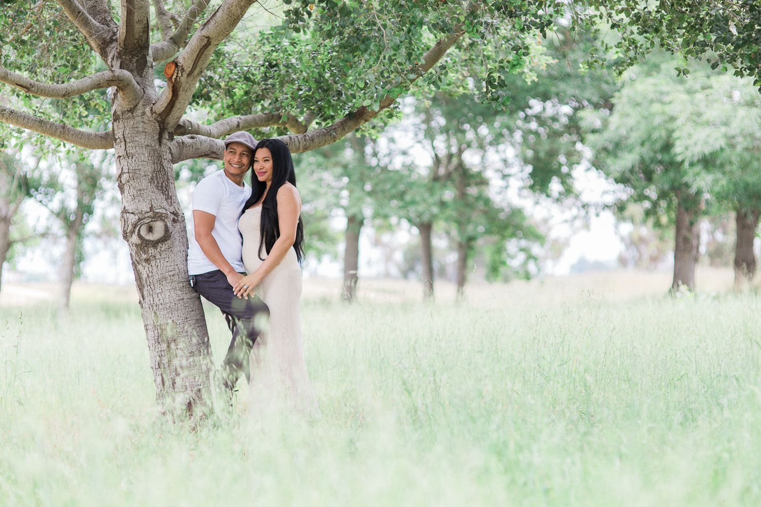 Romantic couple photo session in a misty meadow with tall grass and trees.