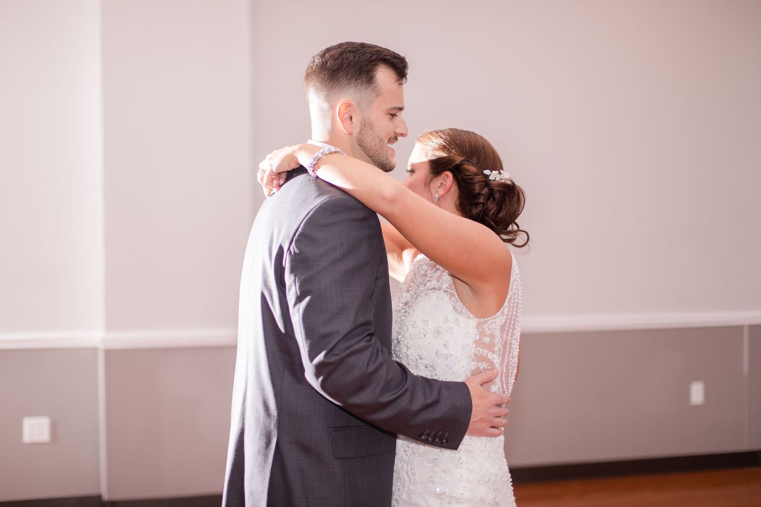 Couple sharing their first dance at a wedding reception in a softly lit ballroom.