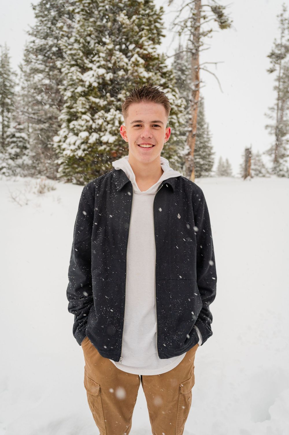 Portrait of someone in casual clothing against a snowy winter forest backdrop.