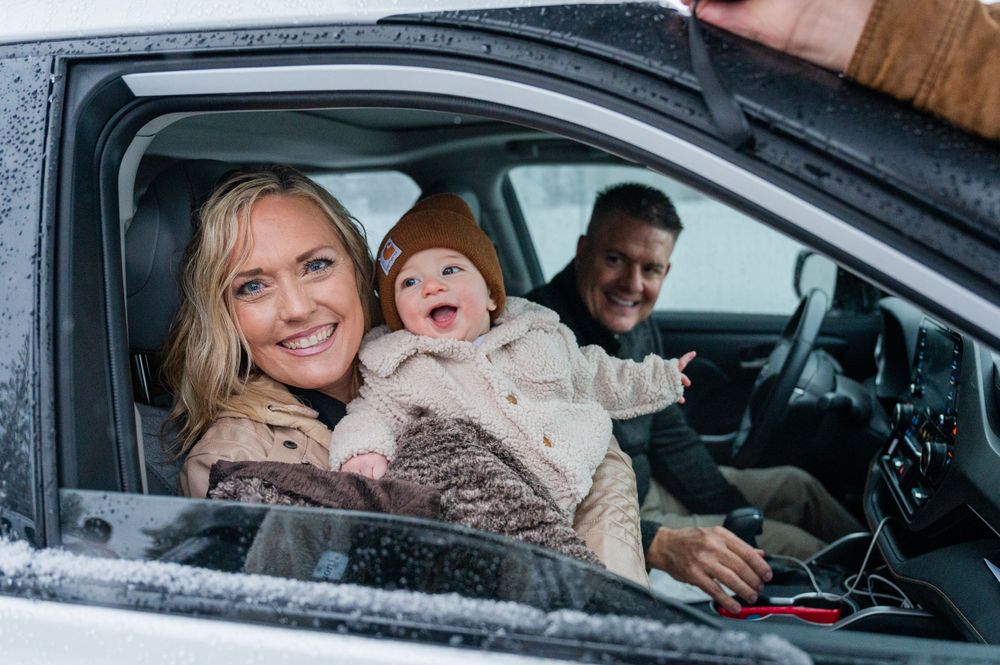 A happy family sitting in a car together during winter weather.
