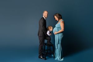 Formal family maternity portrait with toddler  kissing mom's belly