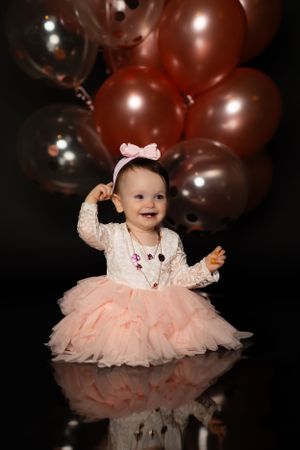 baby girl one year milestone photo with rose gold balloons and pink skirt
