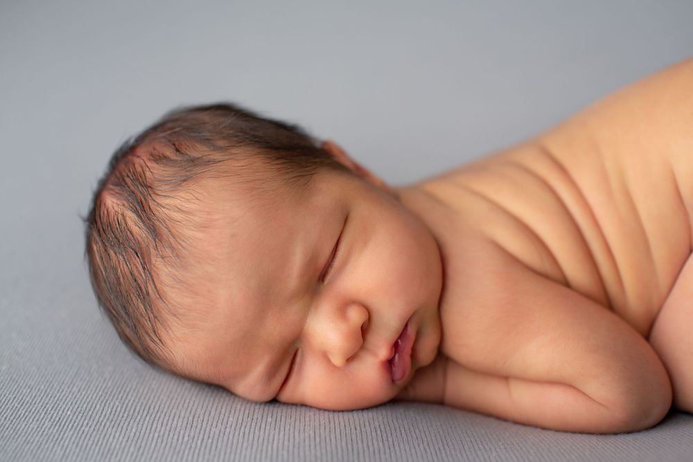 Close-up portrait of sleeping newborn baby on gray textile background.