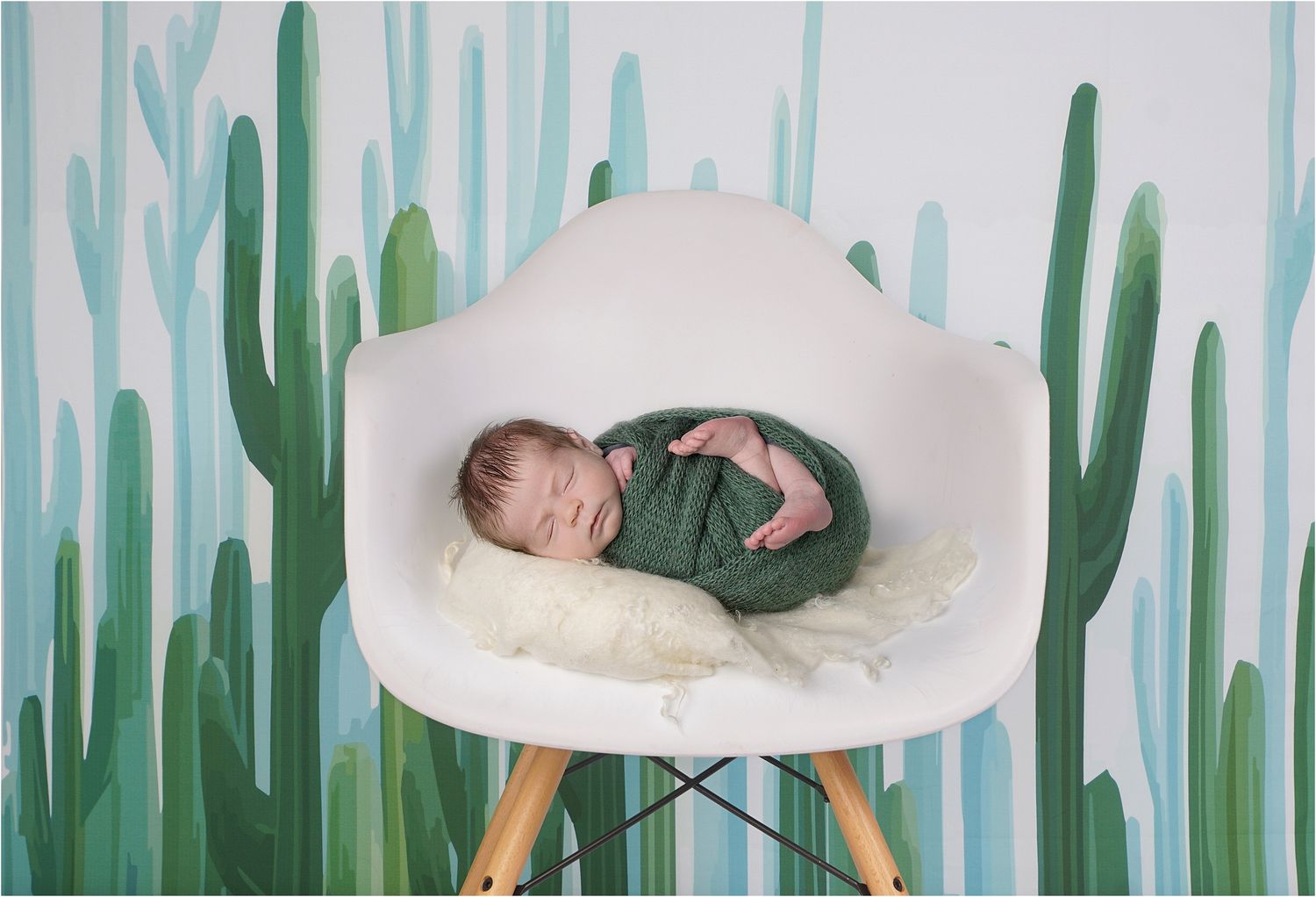 Austin newborn photography session with baby posed in studio chair and green backdrop