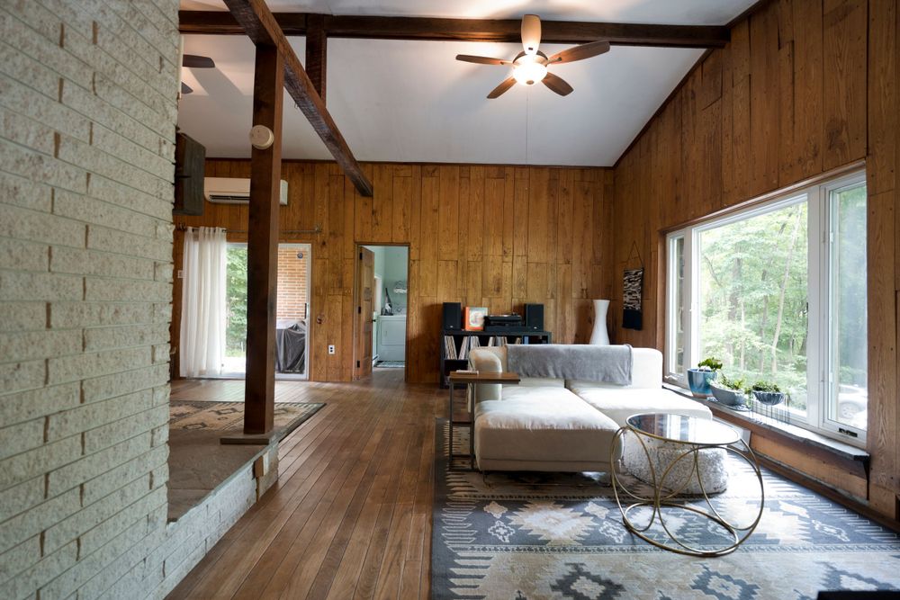 Modern rustic bedroom with wood paneling, large windows and exposed beams.