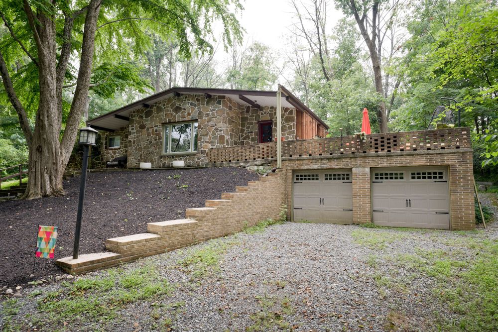 Mid-century stone house with garage and stone steps leading to front entrance.