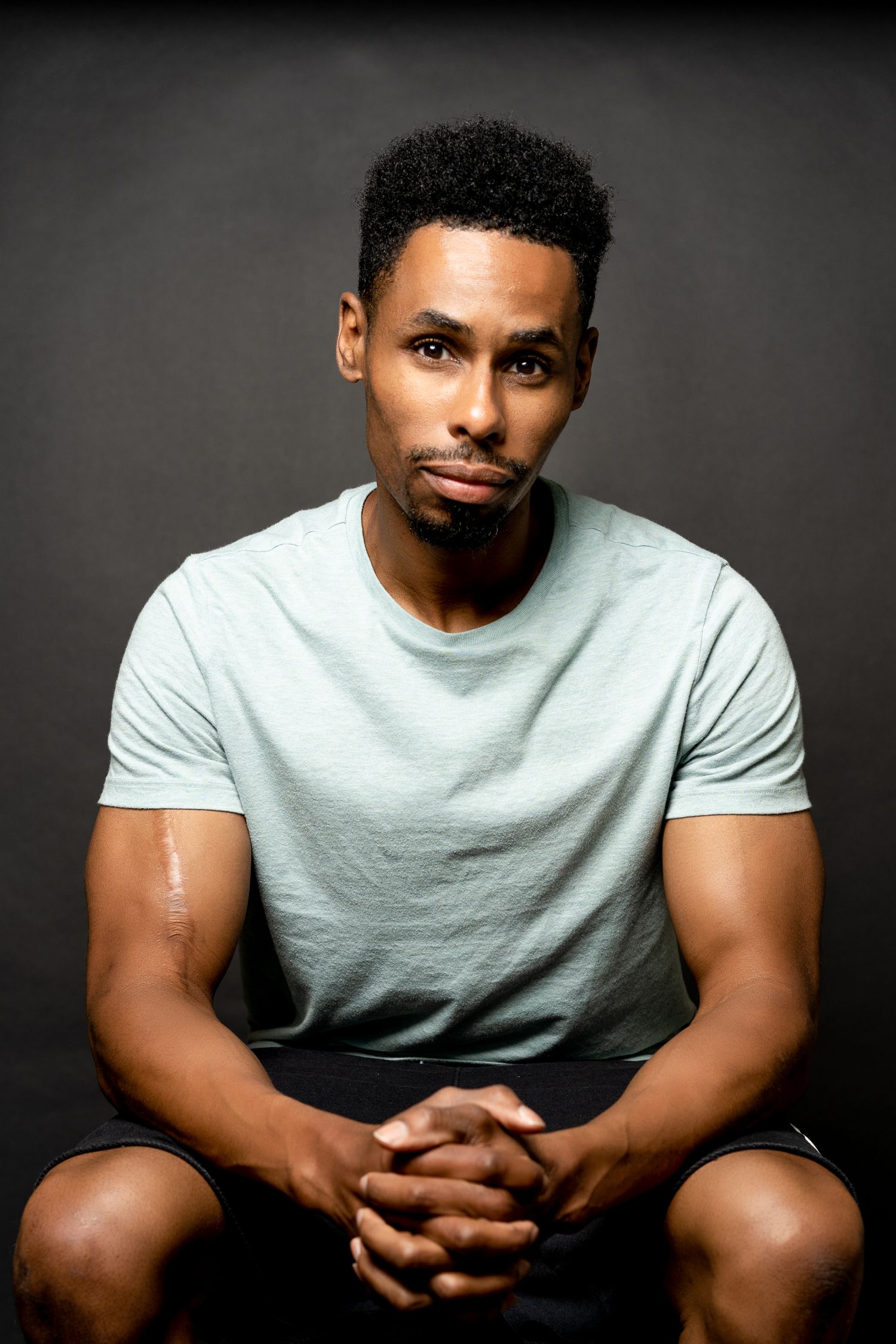 Studio portrait against dark background showcasing casual style and natural lighting.