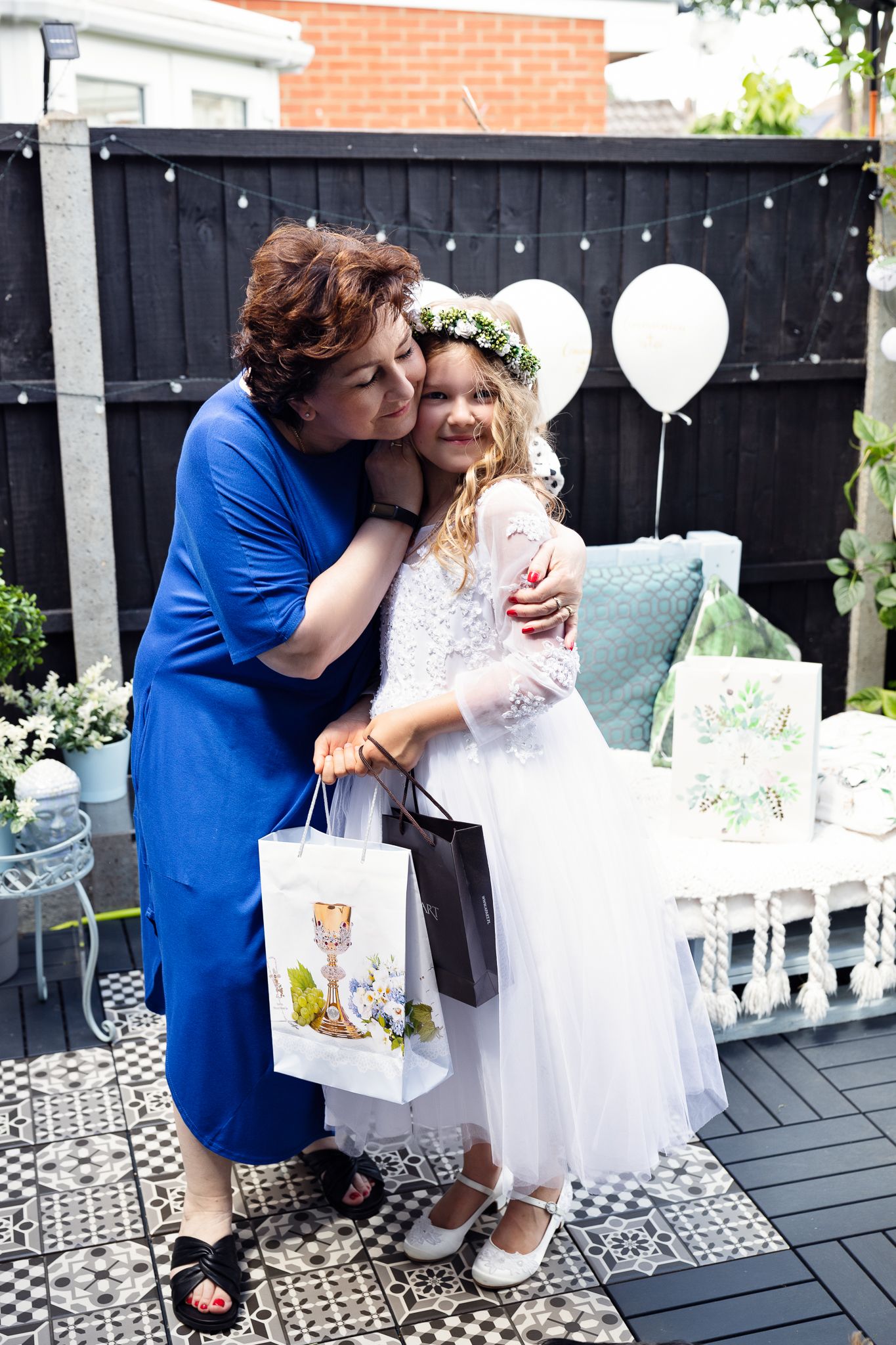 A sweet moment captured on a patterned deck with white balloons and party decorations.