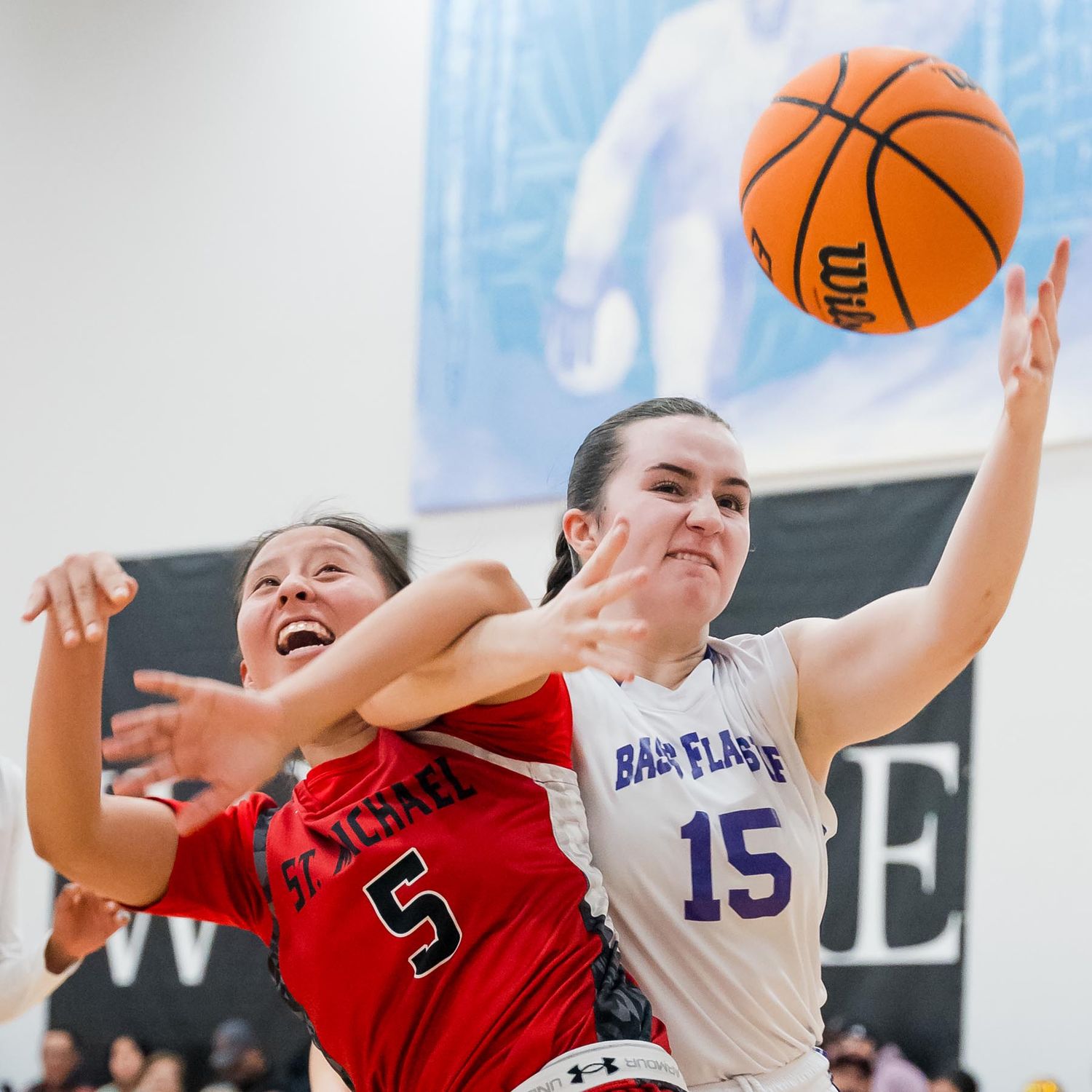Basketball players from opposing teams battle for rebound during competitive game.
