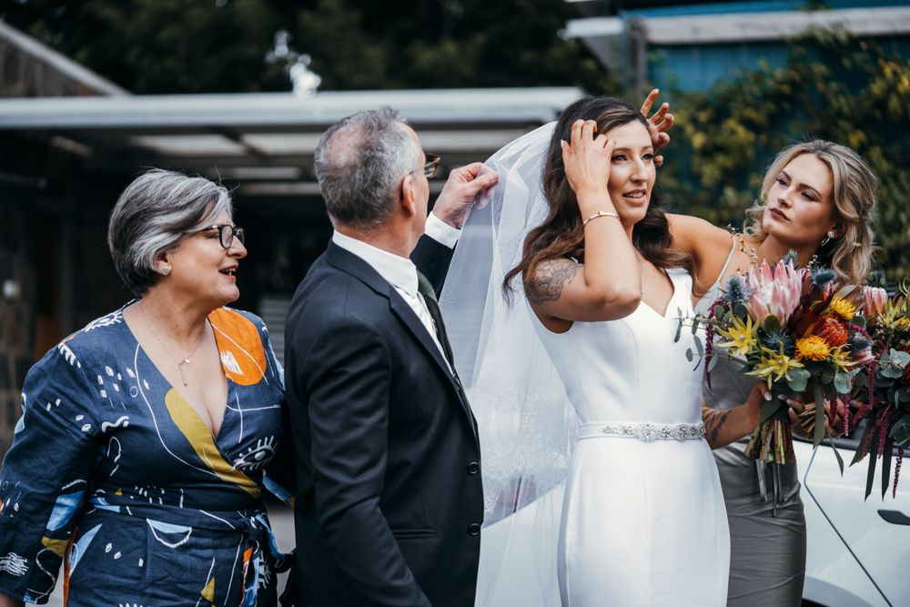 Wedding party members gather outside venue for celebratory photos.