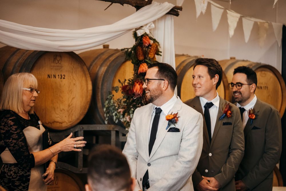 Wedding celebration at rustic venue with wine barrels and decorative white banners.