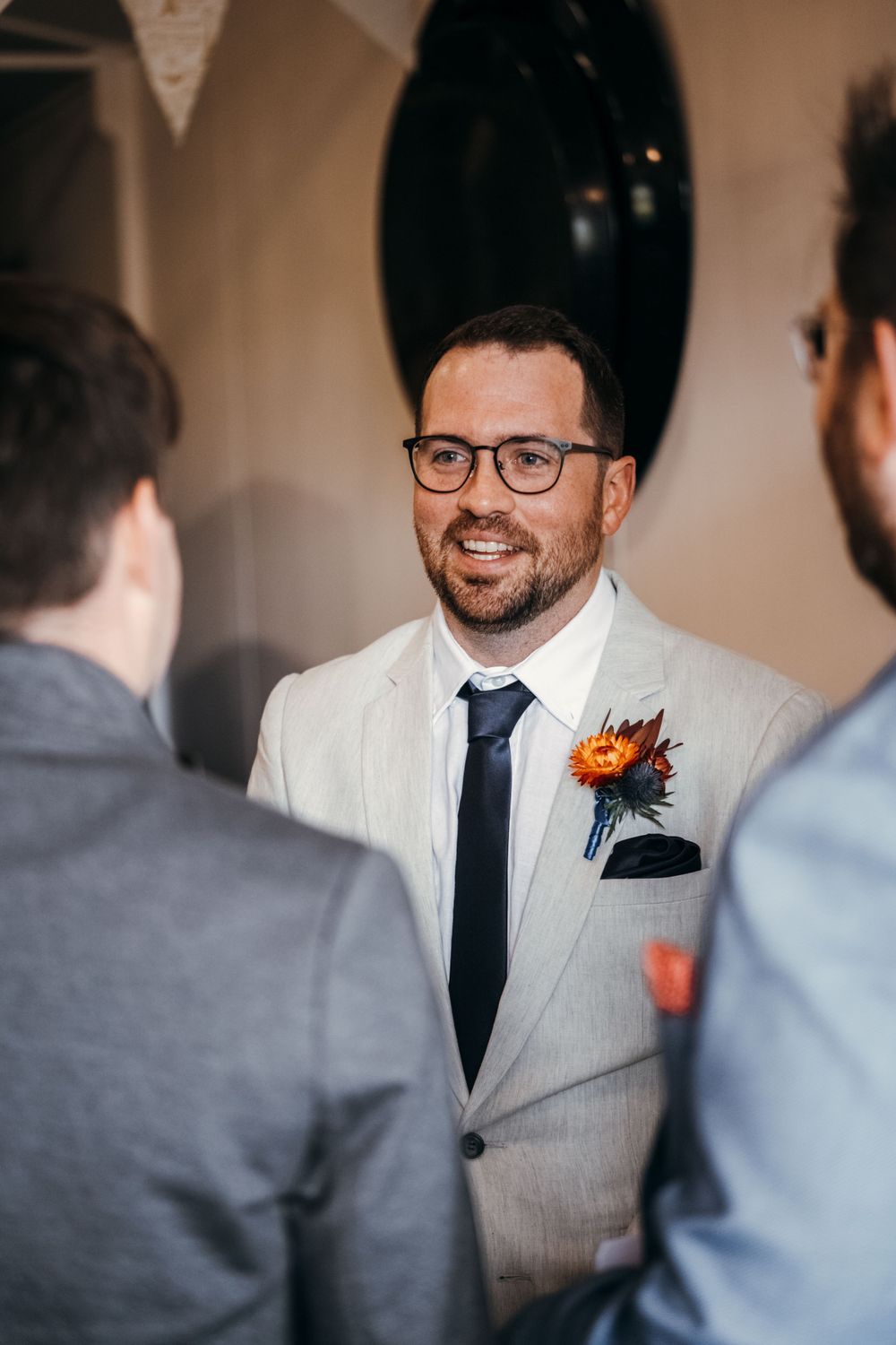 Wedding party members interact and laugh while getting ready in light-filled room.
