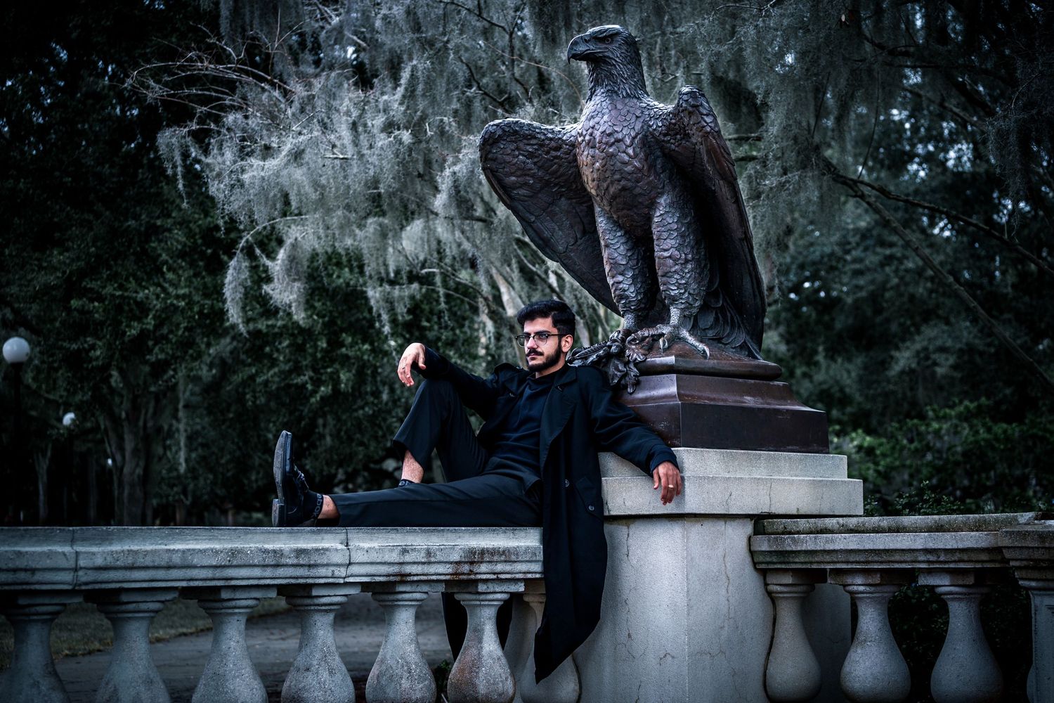 A man dressed in black laying underneath an Eagle Statue