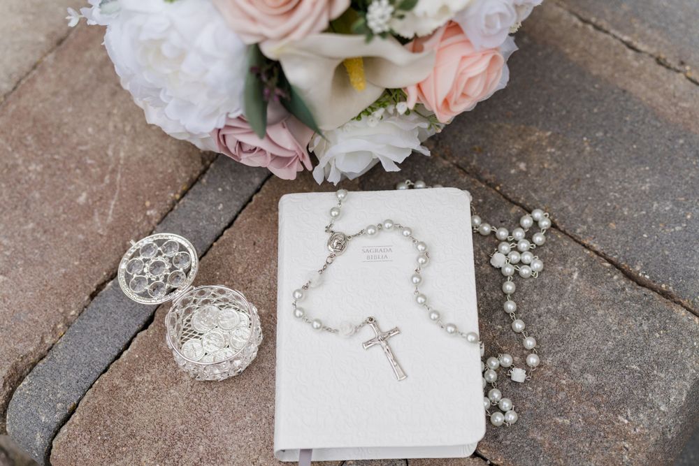 Wedding details including a rosary, bouquet and religious items arranged on stone.
