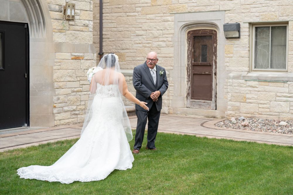 A wedding moment captured outside a stone church building with green lawn.