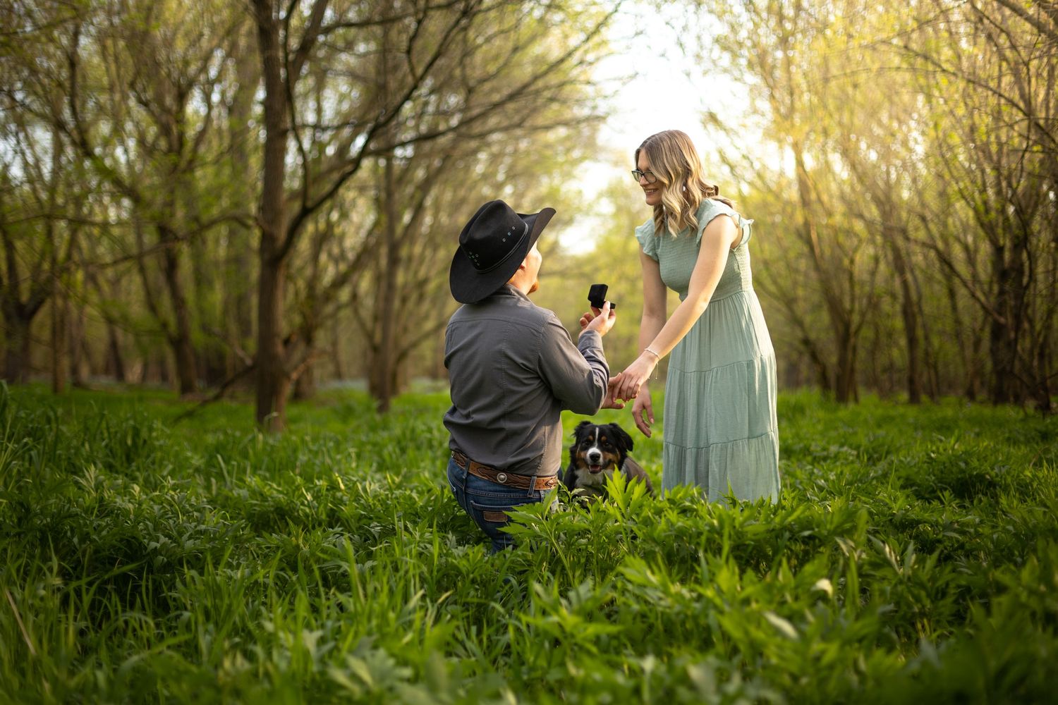 A young cowboy on bended knee proposing to his girlfriend in an Illinois wooded glen.