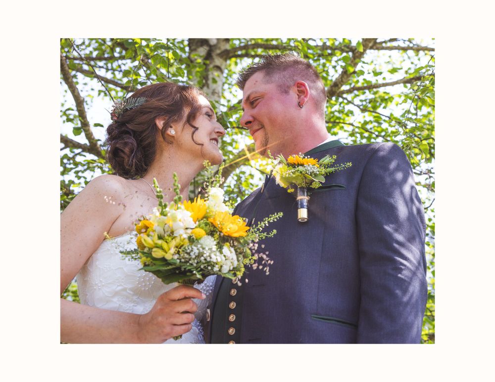 A couple celebrates their wedding day outdoors with bright yellow sunflowers in the bridal bouquet.