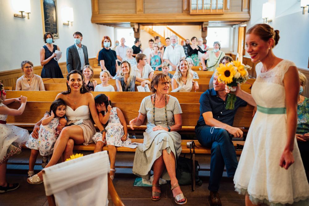 Guests seated in church pews with sunflowers and natural light streaming in.