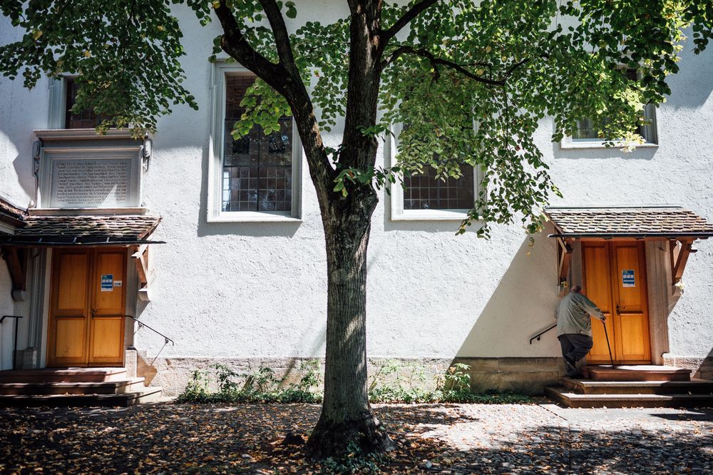 Symmetrical white building exterior with matching orange doors and central tree.