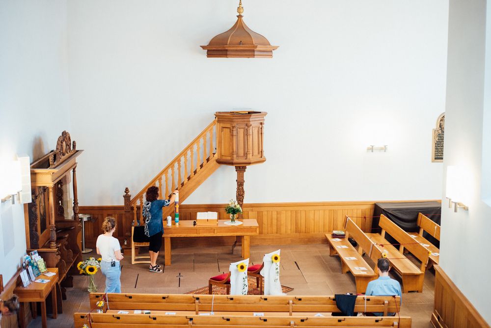 Small chapel interior showing wooden pews and an elevated organ loft with stairs.