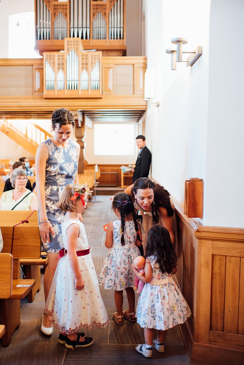 A cheerful scene in a chapel with guests and children in formal attire.