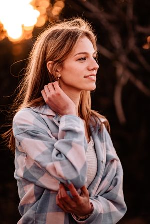 A soft portrait of someone in a plaid shirt at golden hour with sunlit hair and dreamy bokeh background.