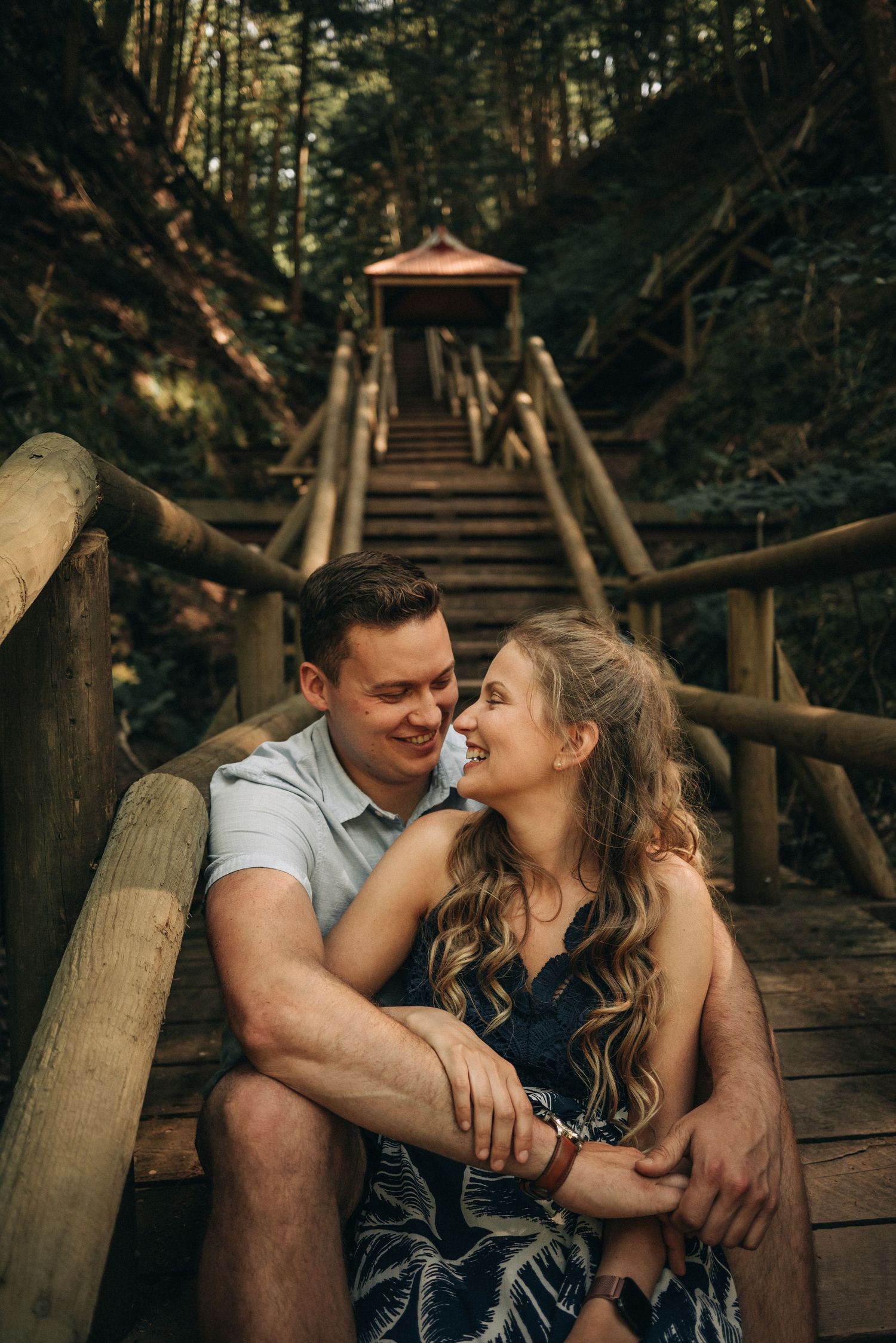 A tender moment shared between a couple on wooden forest stairs.