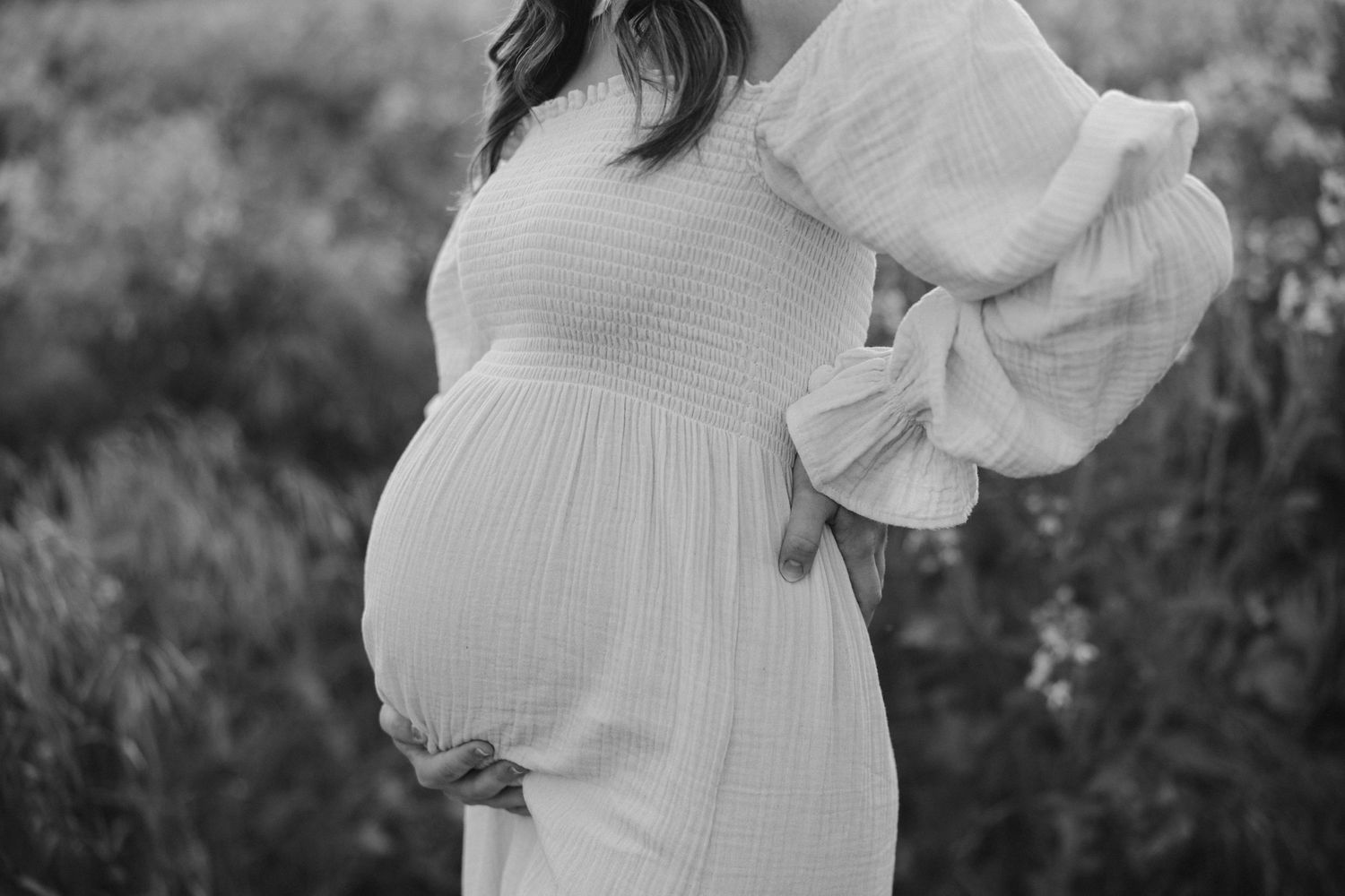 Black and white portrait of pregnant woman in empire waist dress with billowing sleeves.
