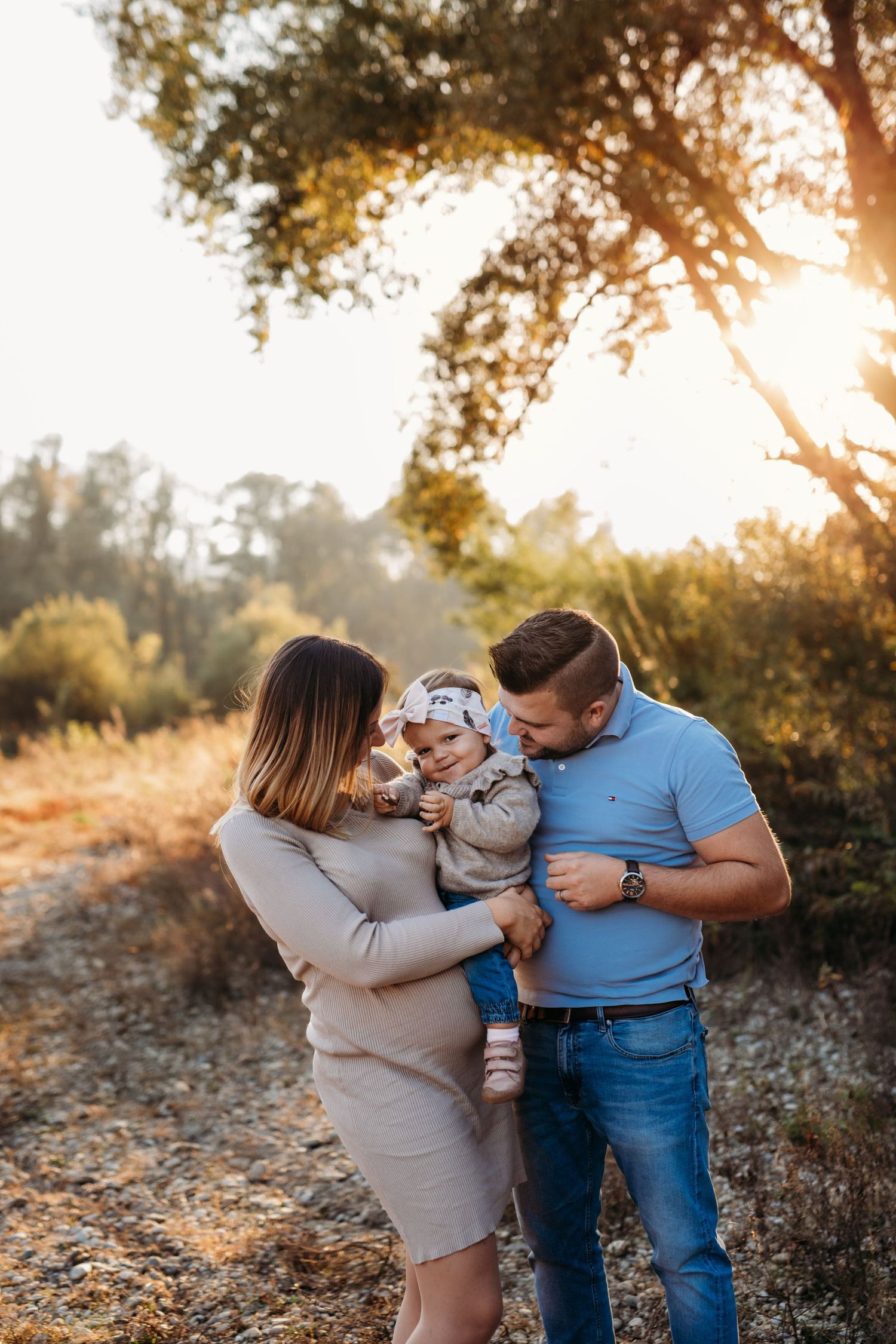 A family shares a tender moment together in a sun-drenched forest setting during golden hour.
