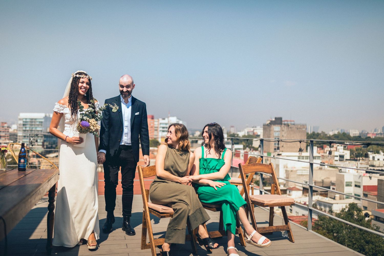 Wedding celebration with guests mingling on sunny urban rooftop.