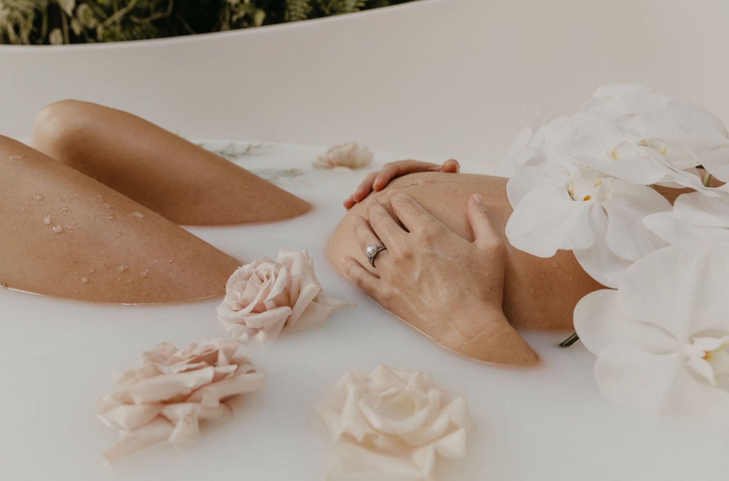 Pregnant belly in milk bath with flowers, in Byron Bay.