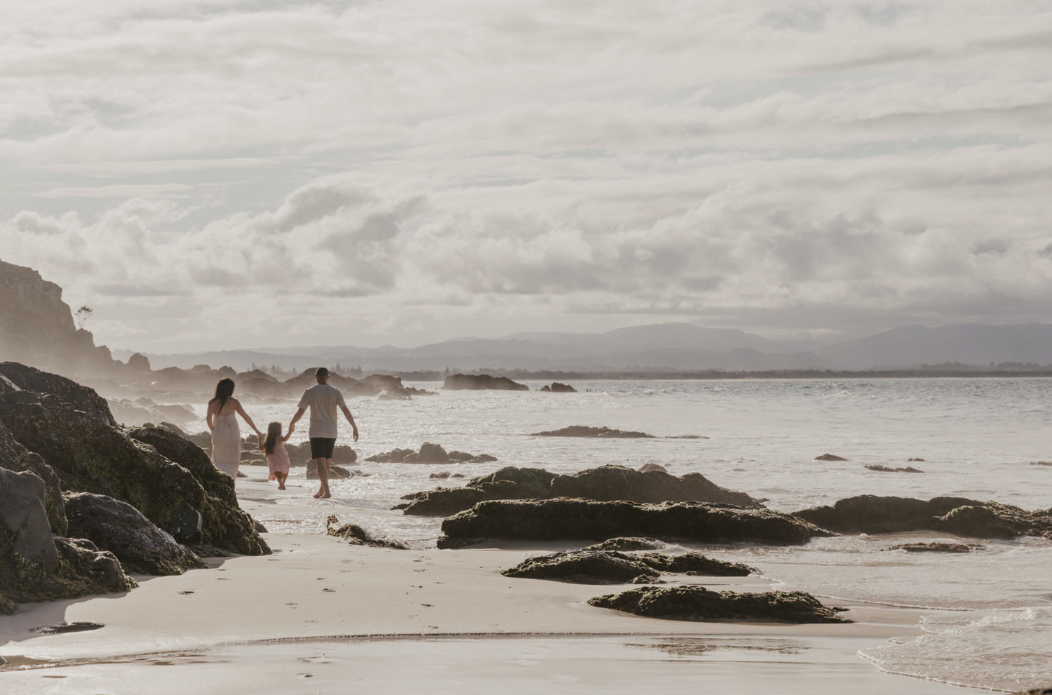 Family walking along the beach in Byron Bay, during sunset.