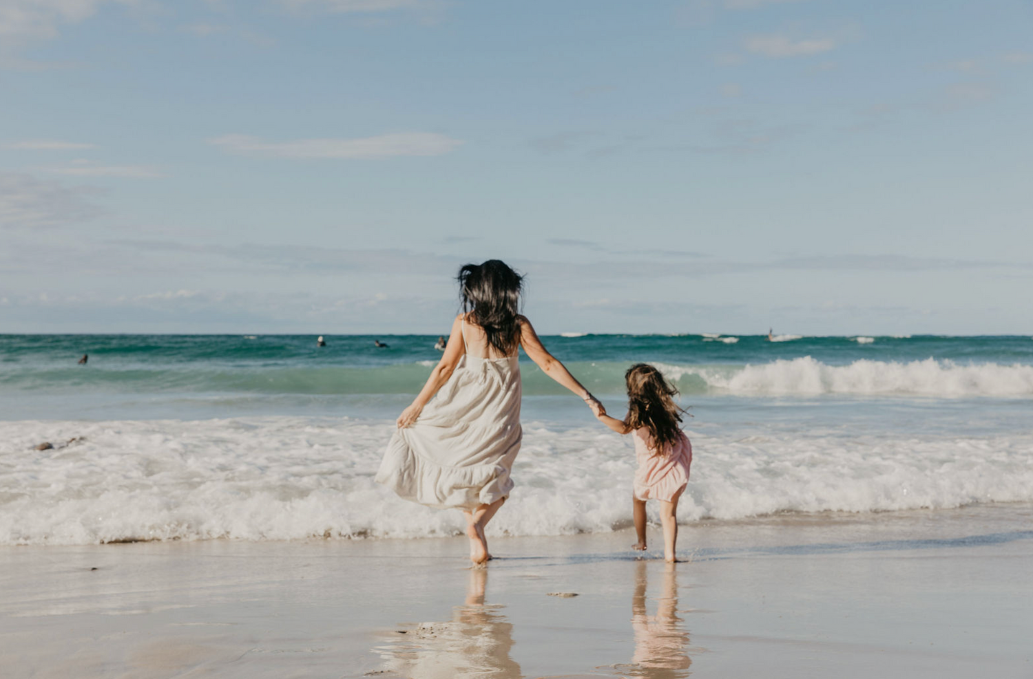 Mother and daughter playing in the ocean, dressed in a casual attire, in Byron Bay.