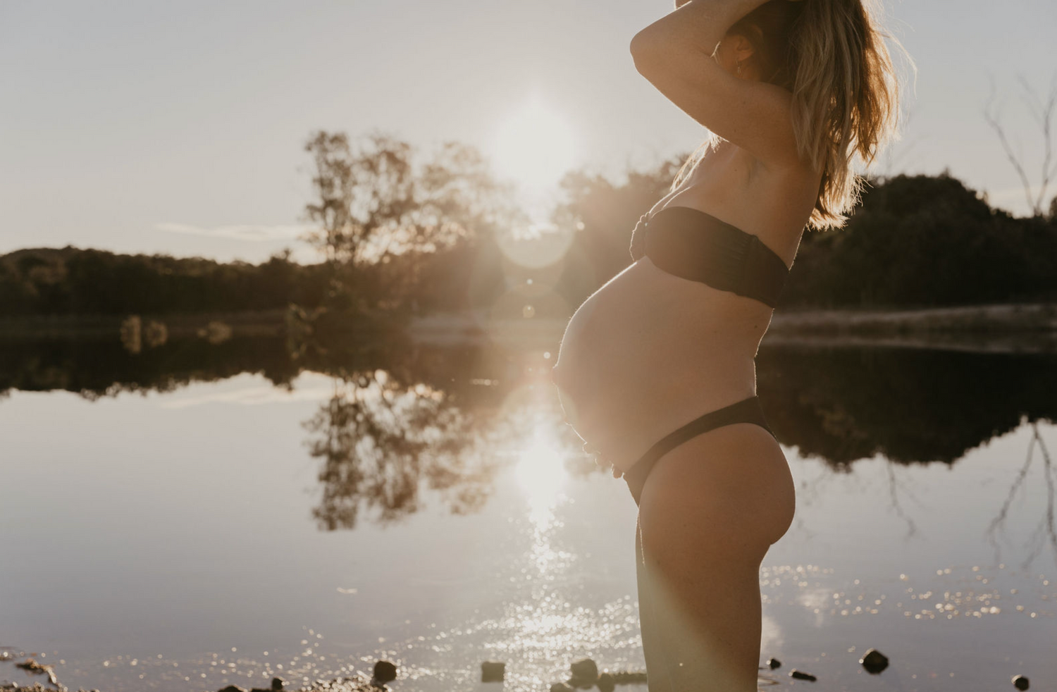 Pregnant mother on the beach near a lake, during sunset in Byron Bay.