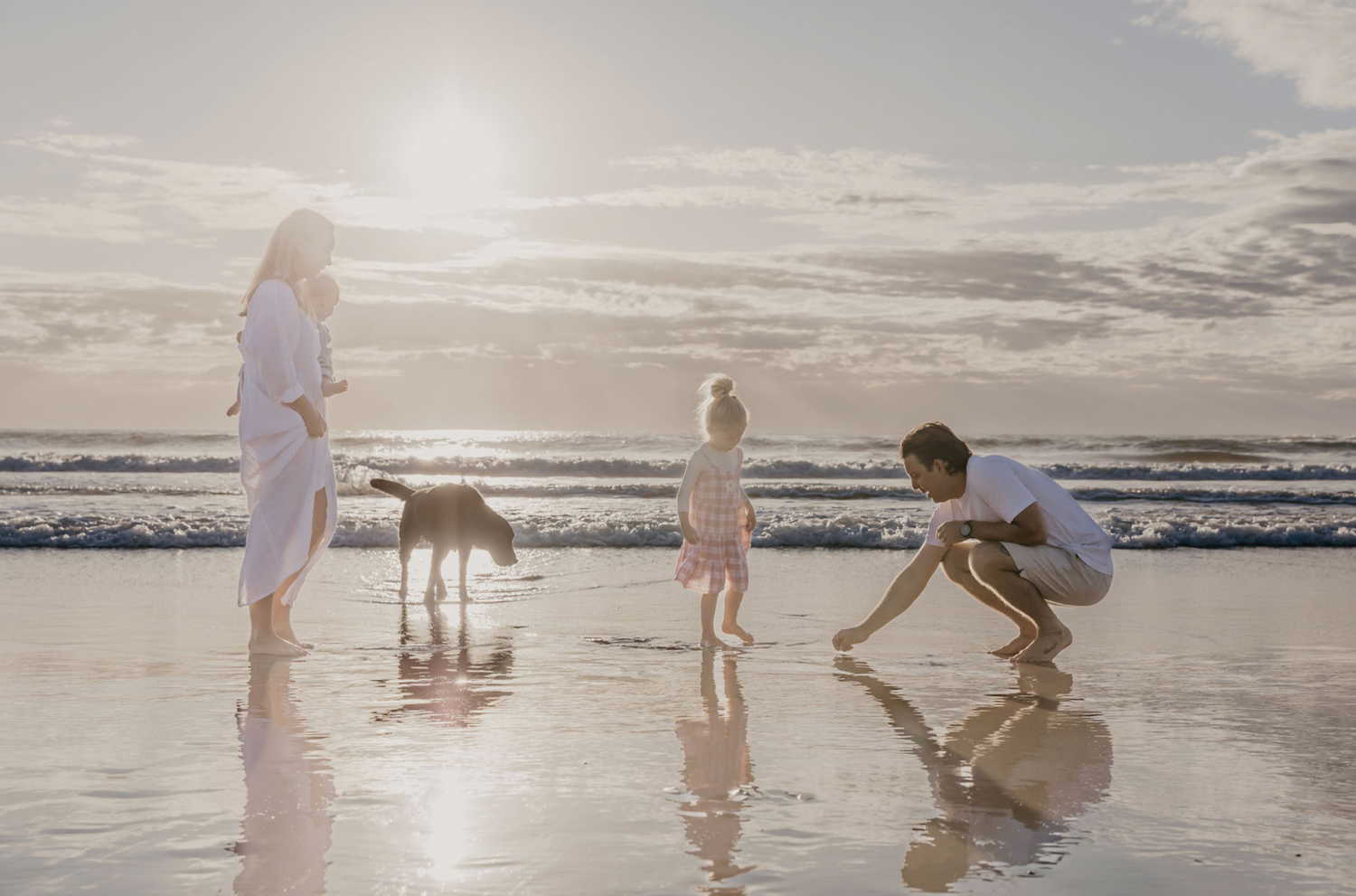 Family sharing a quiet moment together on the beach at sunset in Byron Bay.