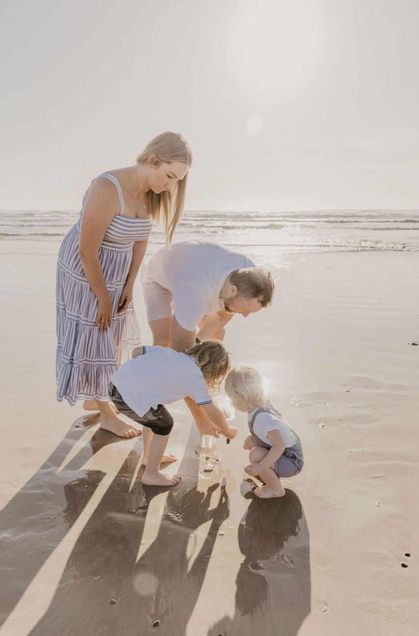 Family sharing a quiet moment together on the beach at sunset in Byron Bay.