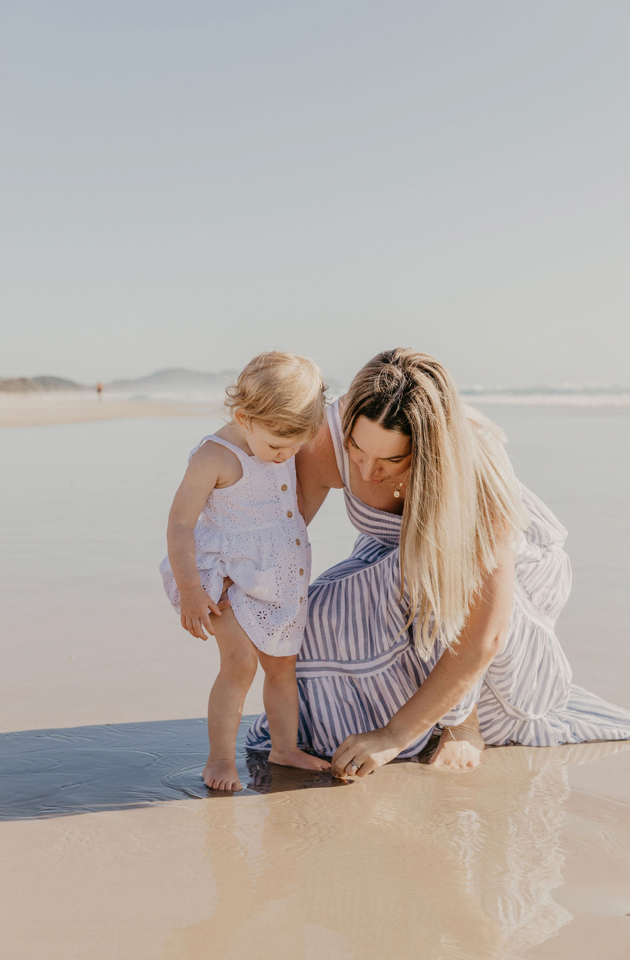 Mother and child sharing a quiet moment together on the beach at sunset in Byron Bay.