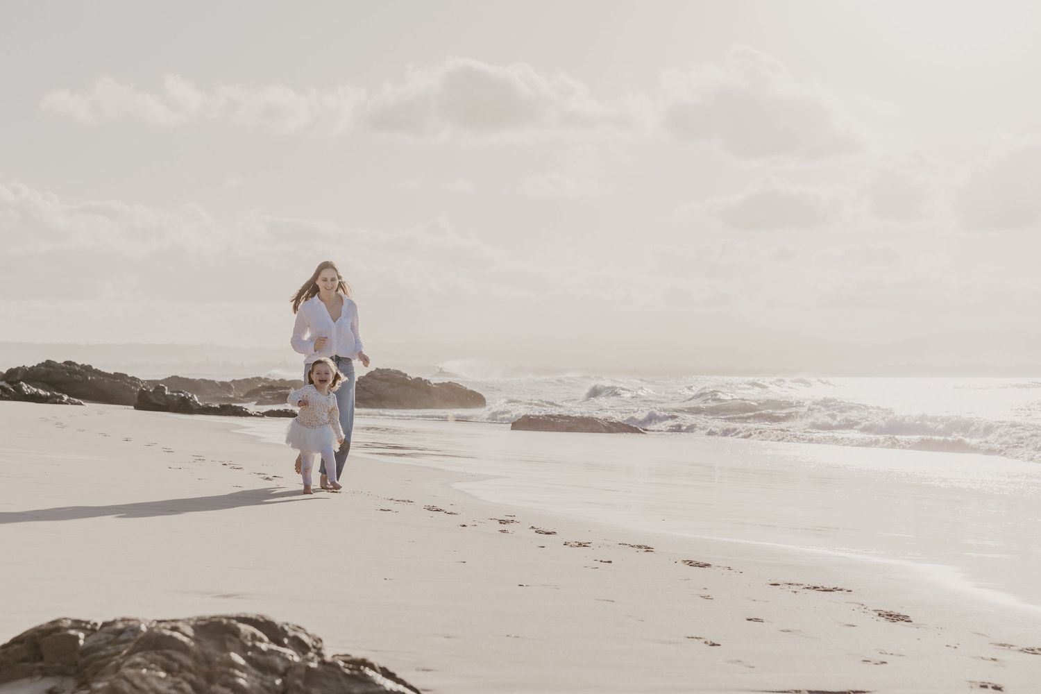 Mother and child sharing a quiet moment together on the beach at sunset in Byron Bay.