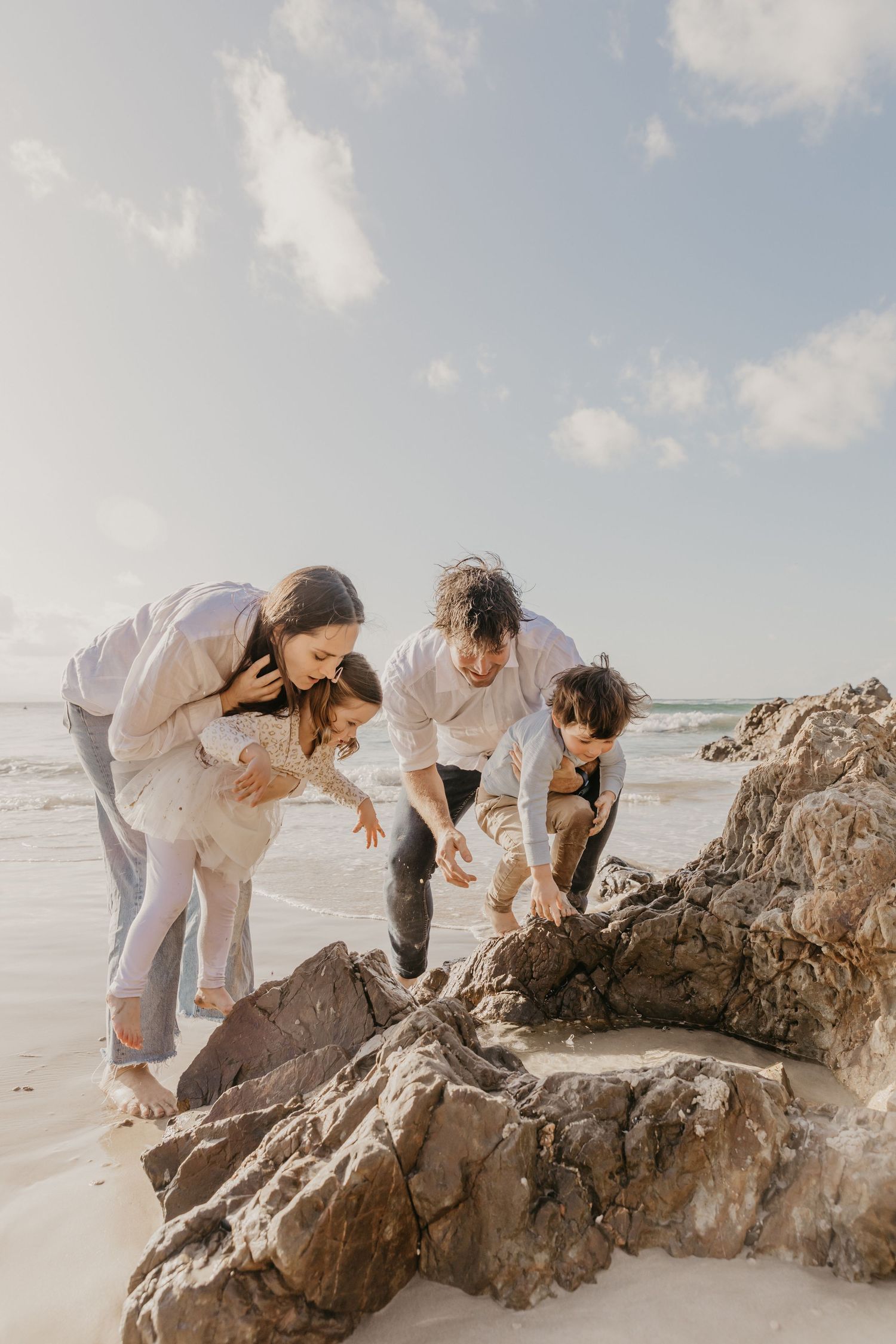 Family sharing a quiet moment together on the beach at sunset in Byron Bay.