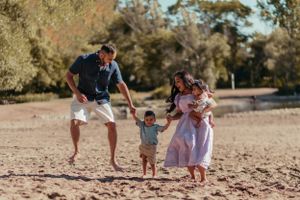 Family playing and running together on a sandy beach during a warm sunny day.