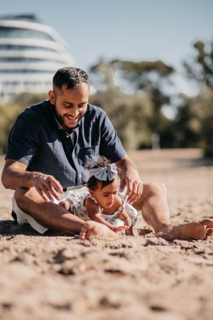 Tender moment between parent and child playing in sand at sunny beach.