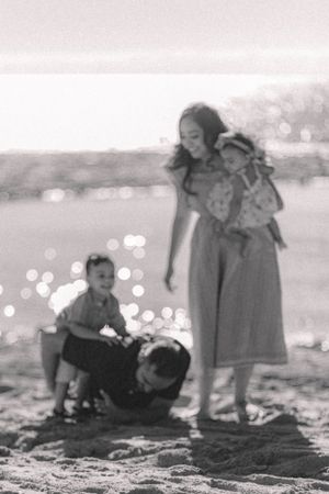 Black and white beach photo capturing a tender family moment with bokeh lights.