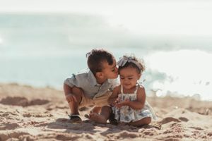 Two small children playing together in the sand at the beach.