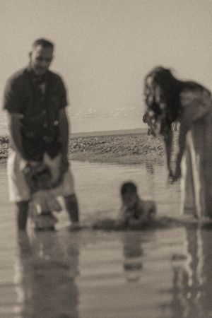 A blurred black and white photo of people playing in shallow water at the beach.