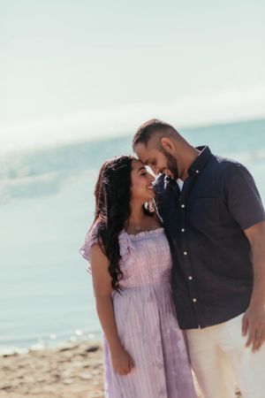 Romantic couple in casual wear sharing intimate moment on sunny beach.