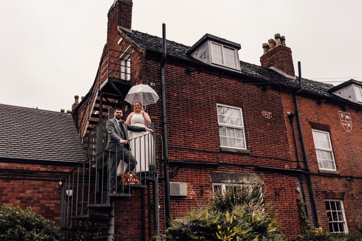 A classic red brick building with white trim and a decorative gate entrance on a cloudy day.
