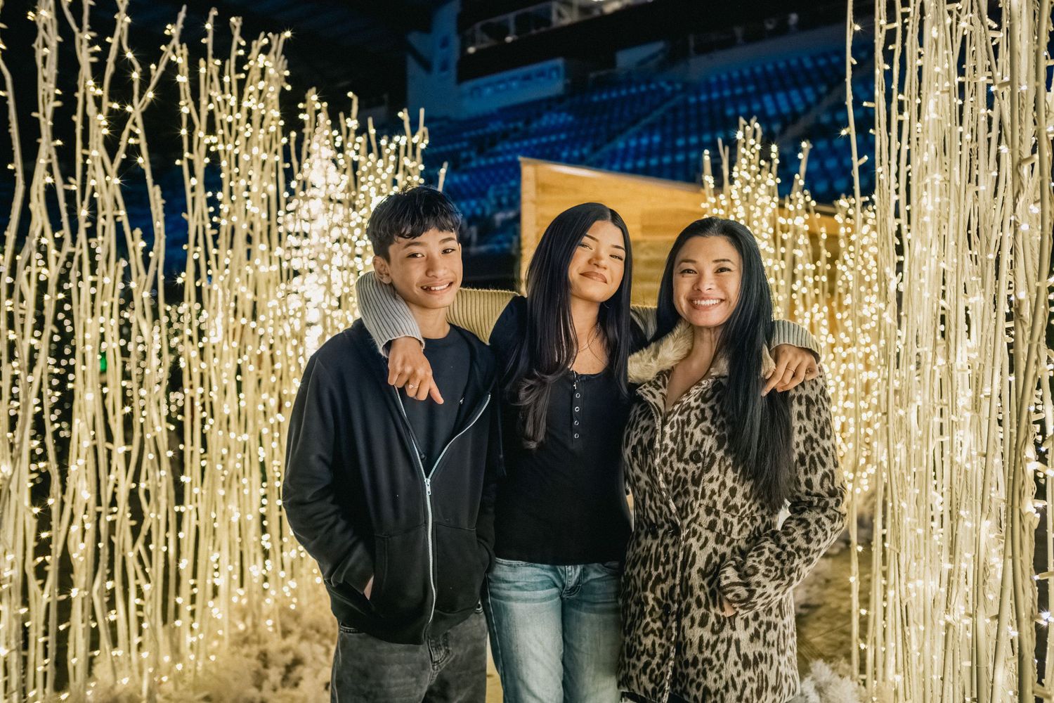 Friends pose together among glowing light installations during a nighttime festival.