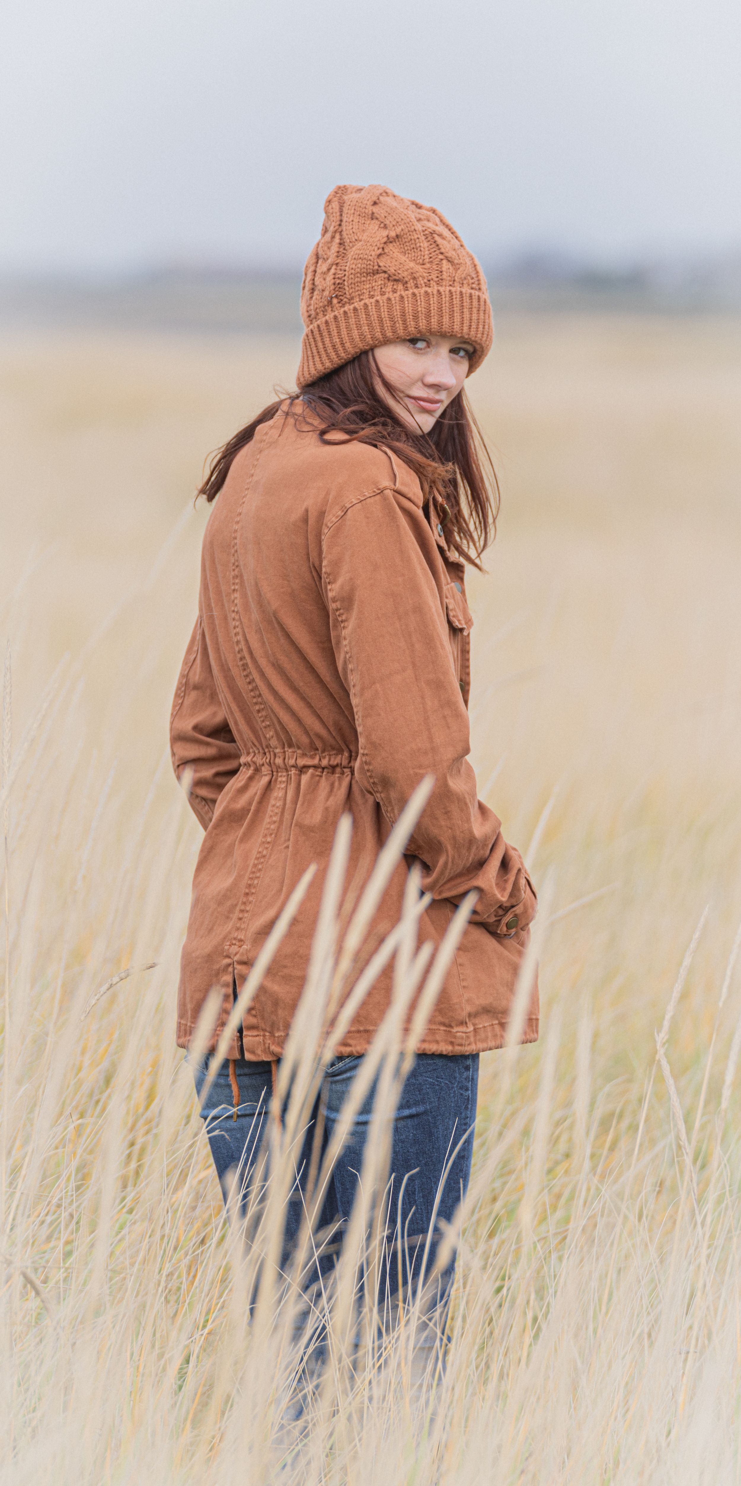 a senior in orange on the beach with soft dreamy background.
