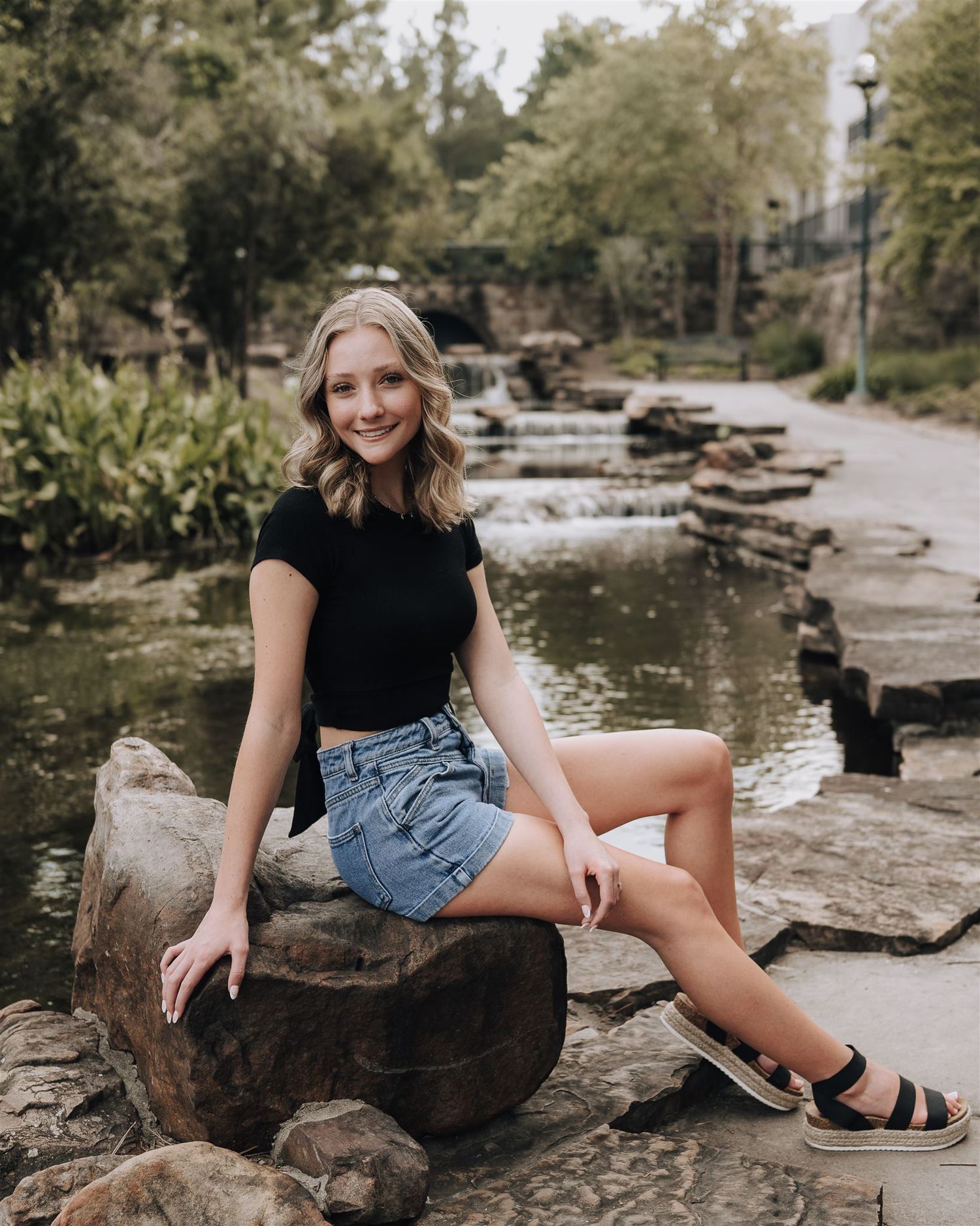 A summer portrait on rocky waterfall steps wearing casual attire.