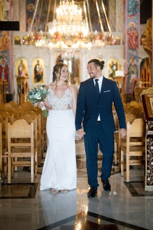 Elegant wedding ceremony in ornate church with crystal chandelier and traditional religious iconography.